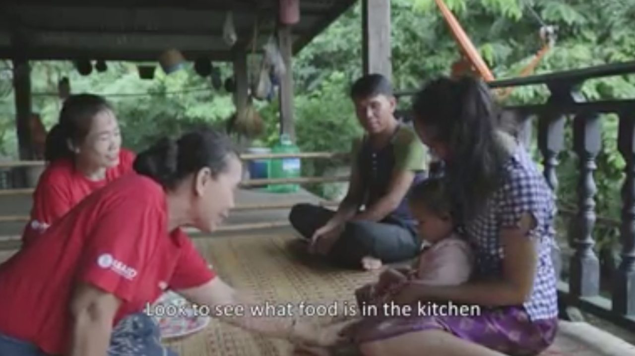 Four Lao people sitting on their porch discussing nutrition